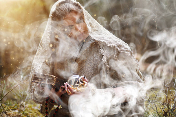Een man in een soutane besteedt een ritueel in een donker bos - Foto, afbeelding