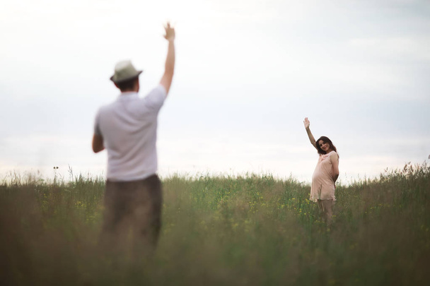 Couple man and pregnant girl in the field - Φωτογραφία, εικόνα