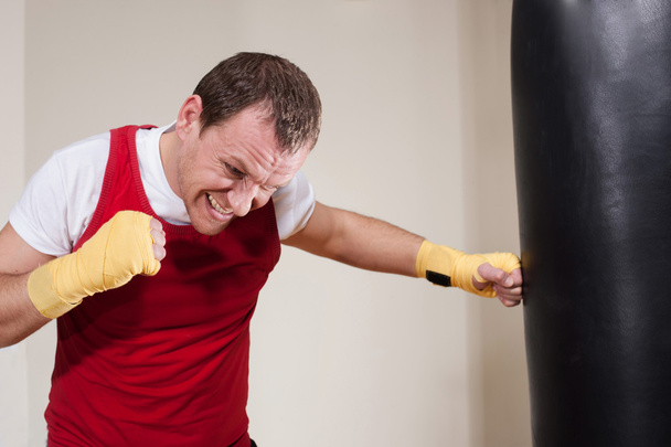 Man in boxing gloves makes a series of exercises with punching b - Photo, image