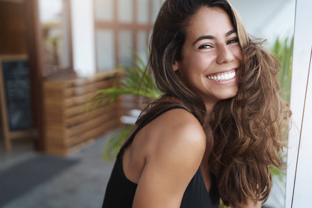 Wellbeing, happiness, beauty concept. Joyful grinning attractive tanned woman white teeth smiling happily look camera laughing talking lovely boyfriend standing veranda, hotel balcony - Photo, Image