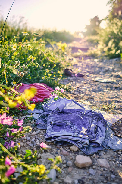 roupas velhas jogadas em um caminho de cascalho com o sol no fundo
 - Foto, Imagem