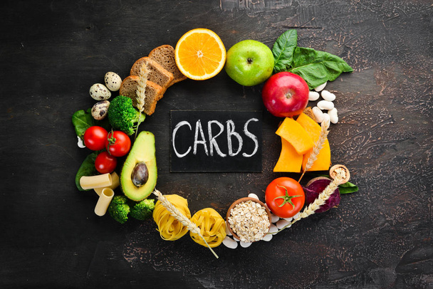 Foods with natural carbohydrates: bread, pasta, avocado, flour, pumpkin, broccoli, beans, spinach. On a brown background. Top view. Free copy space. - Fotó, kép