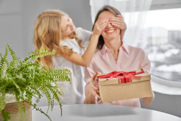 Mother holding present, daughter closing her eyers. - Photo, image