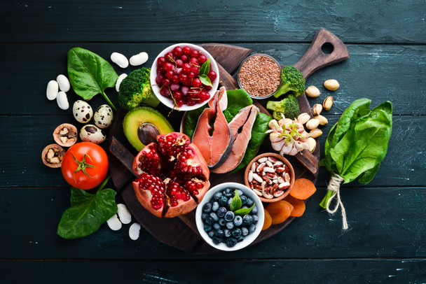 Healthy food: Fish, blueberries, nuts, pomegranate, avocados, tomatoes, spinach, flax. Concept of Dietary Nutrition. Top view. - Foto, Imagem