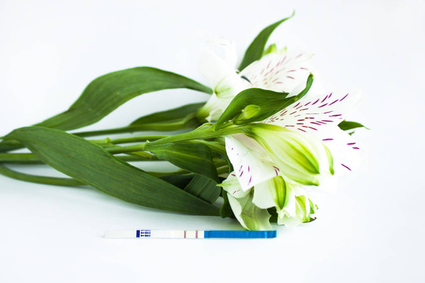 Pozitív terhességi teszt egy csokor fehér Alstroemeria virágok - Fotó, kép