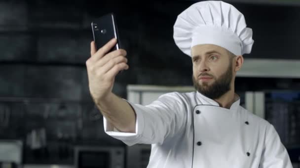 Szef kuchni robi zdjęcie w kuchni. Portret szefa kuchni przy selfie na telefon komórkowy. - Materiał filmowy, wideo