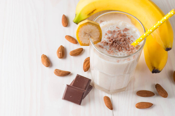 Vers gemaakte chocolade banaan Smoothie op een houten tafel. Selectieve aandacht. Milkshake met amandelen. Eiwit dieet. Gezond eten en drinken concept. - Foto, afbeelding