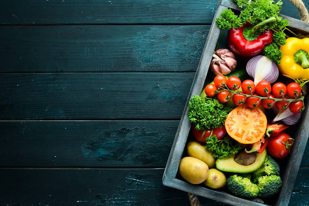 Fresh vegetables and fruits in a wooden box. Avocados, tomatoes, strawberries, melons, potatoes, paprika, citrus. Top view. Free space for your text. - Foto, Imagen