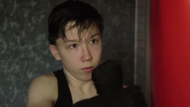Een tiener in een zwart t-shirt in bokstraining. Slow Motion - Video
