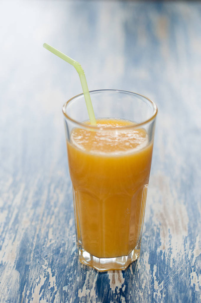 Γυαλί χυμό πορτοκάλι με άχυρο σε μπλε ξύλινο φόντο Aqua - Φωτογραφία, εικόνα