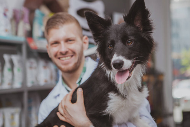 Щасливий красивий чоловічий ветеринар насолоджується роботою зі своїм собакою-пацієнтом
 - Фото, зображення