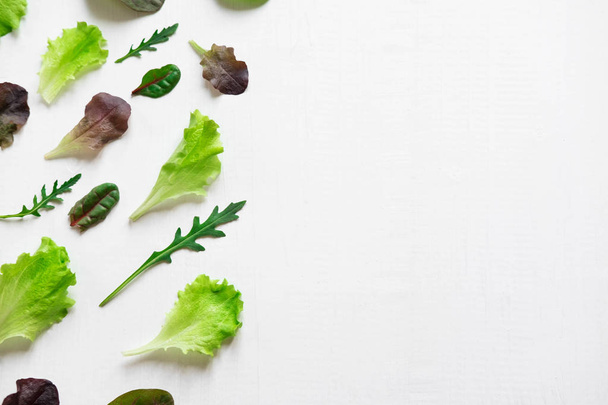 Pattern with lettuce for the background on the site. Salad greens and dietary products. Proper nutrition and vegetarianism. Background with lettuce leaves. Flat lay, top view. - Photo, image