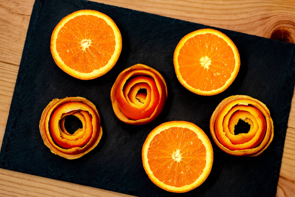 マンダリンは、皮の柑橘類の装飾と暗い石の上に提供されています。プレート上の半分のみかんとスパイラルの皮。クローズ アップ。ソフトフォーカス。トップビュー. - 写真・画像