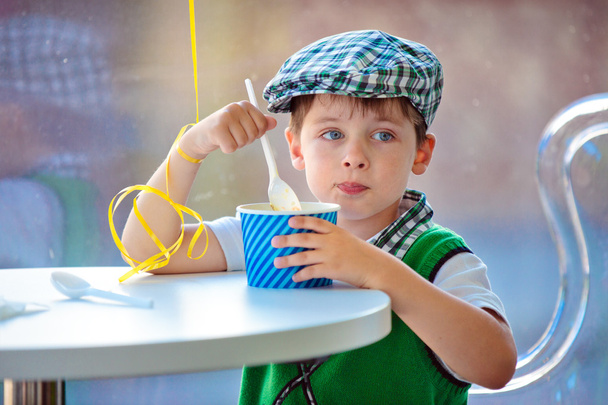 Cute little boy eating ice cream at indoor cafe - Фото, зображення