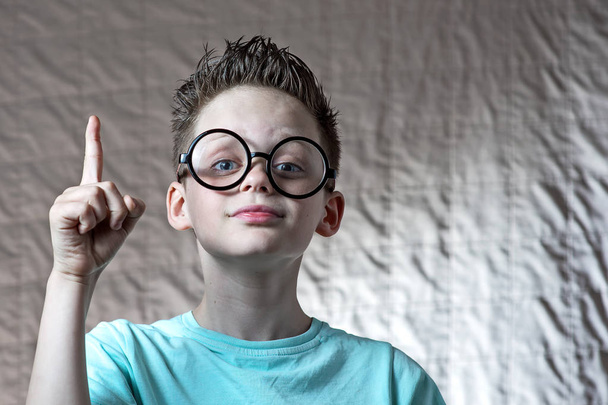 boy in a light t-shirt and round glasses raised his index finger he had an idea - 写真・画像