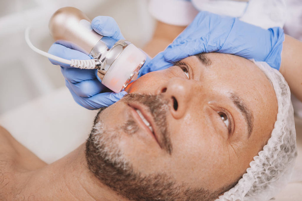 Mid-aged male client enjoying hardware cosmetology treatment - Фото, зображення