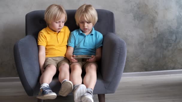A testvérek figyelnek, játszanak vagy tanulnak valamit egy okostelefonon. - Felvétel, videó