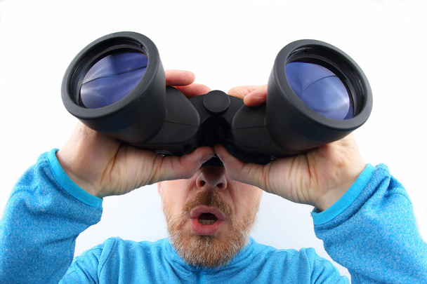 Hombre barbudo mirando a través de binoculares sobre fondo blanco
 - Foto, imagen