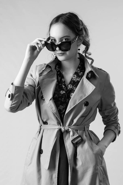Muchacha joven atractiva en un abrigo y gafas de sol
 - Foto, Imagen