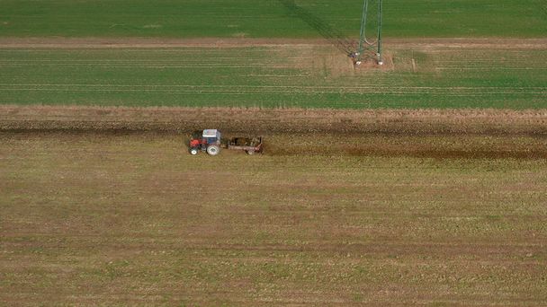 Letecký pohled na červený traktor a přívěs s nákladem hnoje na silnici - Fotografie, Obrázek