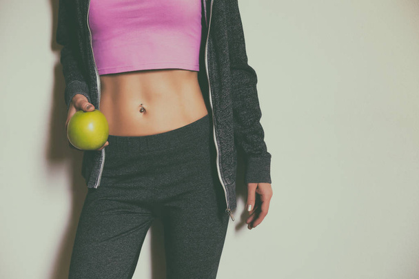 Fit sporty woman with abs holding apple. - Foto, afbeelding