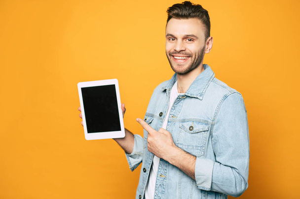 Side view portrait of casual business man with modern tablet in hands over yellow background - Φωτογραφία, εικόνα