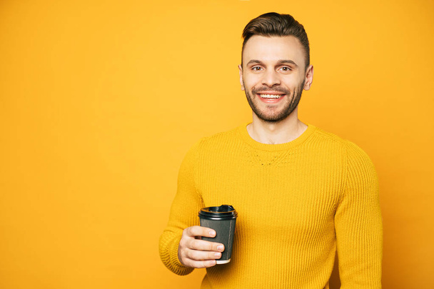 Smiling young student man with cup of coffee looks on camera - Zdjęcie, obraz