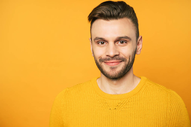 Close up portrait of happy handsome man in yellow is posing over orange background - Foto, afbeelding