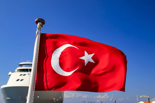 Bandeira Nacional Vermelha da Turquia com meio mês e uma estrela contra o céu e um transatlântico, símbolo de estado turco, outono, primavera, verão
 - Foto, Imagem