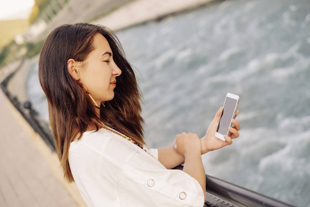 Женщина с мобильного телефона на набережной реки
  - Фото, изображение