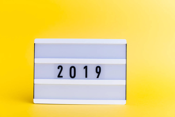 Foto de una caja de luz con texto, 2019, sobre fondo amarillo aislado
 - Foto, Imagen