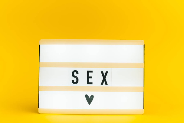 Foto van een lichtbak met tekst, seks, op geïsoleerde gele achtergrond - Foto, afbeelding