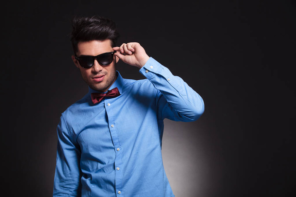 Charming young male standing and fixing his sunglasses - Photo, Image