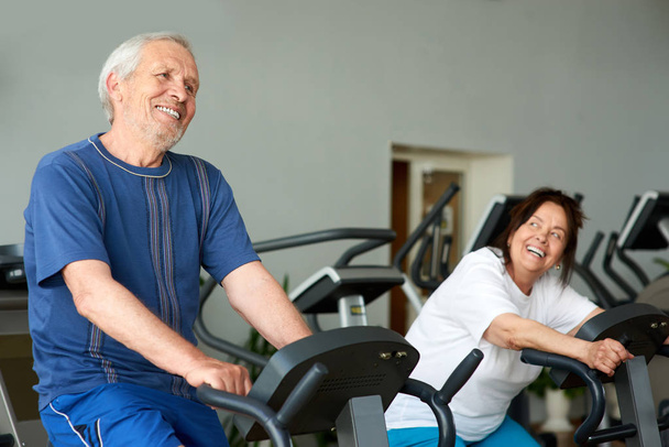Cheerful couple of seniors training at gym. - Фото, зображення