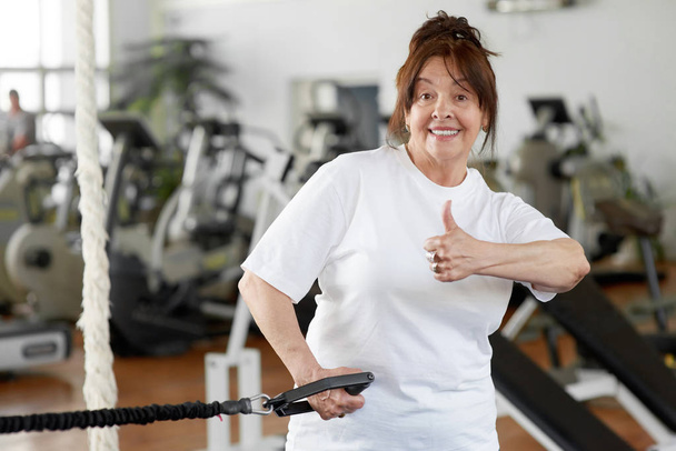 Oudere vrouw in Gym toont duim omhoog. - Foto, afbeelding