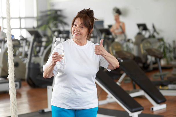 Active woman giving thumb up in gym. - Photo, image
