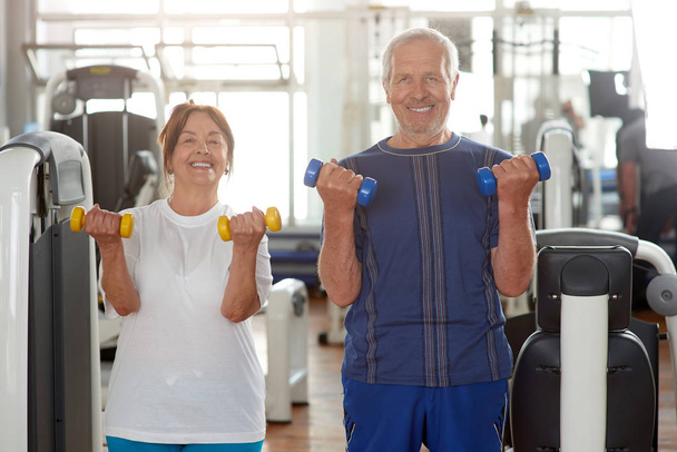 Πορτρέτο του χαμογελαστή ζευγάρι ηλικιωμένων στο γυμναστήριο. - Φωτογραφία, εικόνα