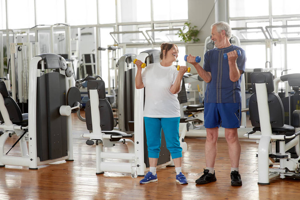 Happy senior couple lifting dumbbells at gym. - Photo, Image
