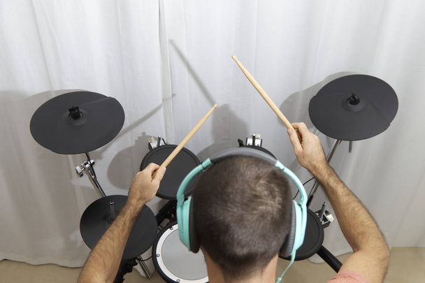 Drumor con bastones y auriculares en una escuela de música. - Foto, imagen