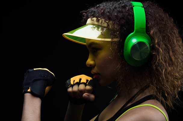 Спортивная девушка афро-американка слушает музыку на наушниках и готовится к бою
. - Фото, изображение