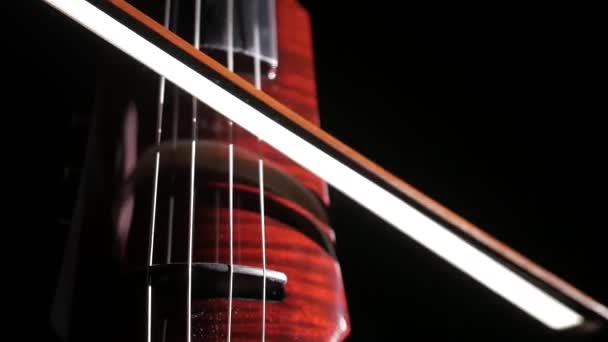 Hand eines Mannes, der ein elektrisches Cello auf schwarzem Hintergrund spielt, Nahaufnahme von Saiten, Bogen und Griffbrett, isoliert - Filmmaterial, Video