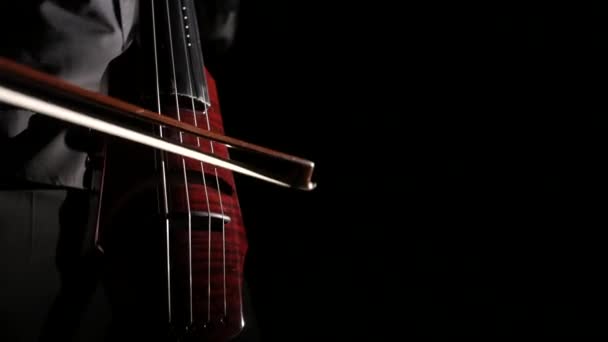 hand of a man playing an electric cello on a black background, close-up of strings, bow and fingerboard, isolated - Footage, Video