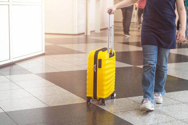 Το κορίτσι είναι στο αεροδρόμιο με φωτεινή και κομψή βαλίτσα σε μέγεθος καμπίνας ως ιδέα διακοπών - Φωτογραφία, εικόνα