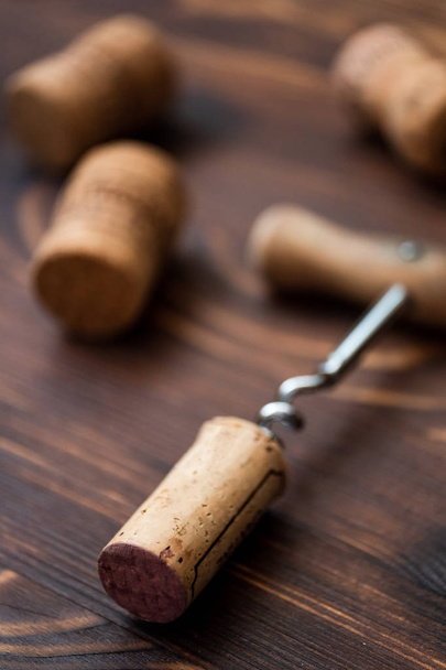 Corkscrew and corks on a wooden background. - Photo, Image