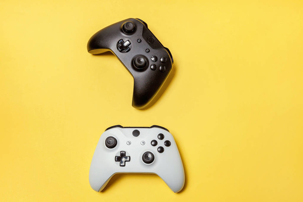 黄色の背景に白と黒の2つのジョイスティック。コンピュータゲーム競技大会ビデオゲーム制御対決コンセプト - 写真・画像