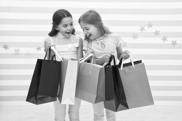 Discount concept. Kids cute girls hold shopping bags. Shopping discount season. Spending great time together. Children satisfied shopping striped background. Obsessed with shopping and clothing malls - Фото, изображение