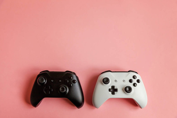 Valkoinen ja musta kaksi joystick vaaleanpunainen tausta. Tietokonepelien kilpailu videopelien valvonta vastakkainasettelu käsite
 - Valokuva, kuva