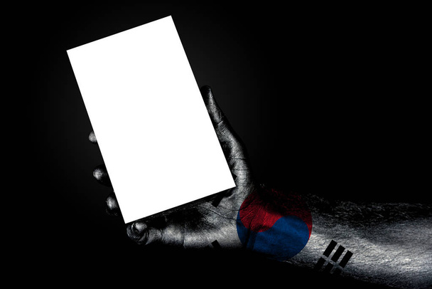 χέρι με βαμμένη σημαία Νότια Κορέα κρατώντας ένα μεγάλο λευκό φύλλο με χώρο για μια επιγραφή, μακέτα - Φωτογραφία, εικόνα