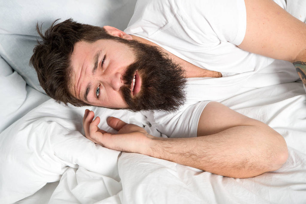 おはようございます。リラックスして睡眠の概念。髭を生やした男が白いシーツの上で寝ている。健康的な睡眠と幸福。男は腰をベッドの中で眠く髭を生やした。早朝の時間だ。不眠症と睡眠障害 - 写真・画像