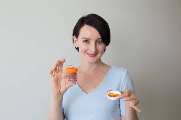 Jovem amigável retrato feminino mão segurando pílulas laranja
 - Foto, Imagem